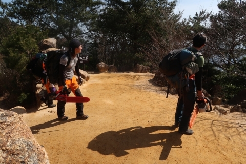 チェーンソーを持ちながら登山する人の様子